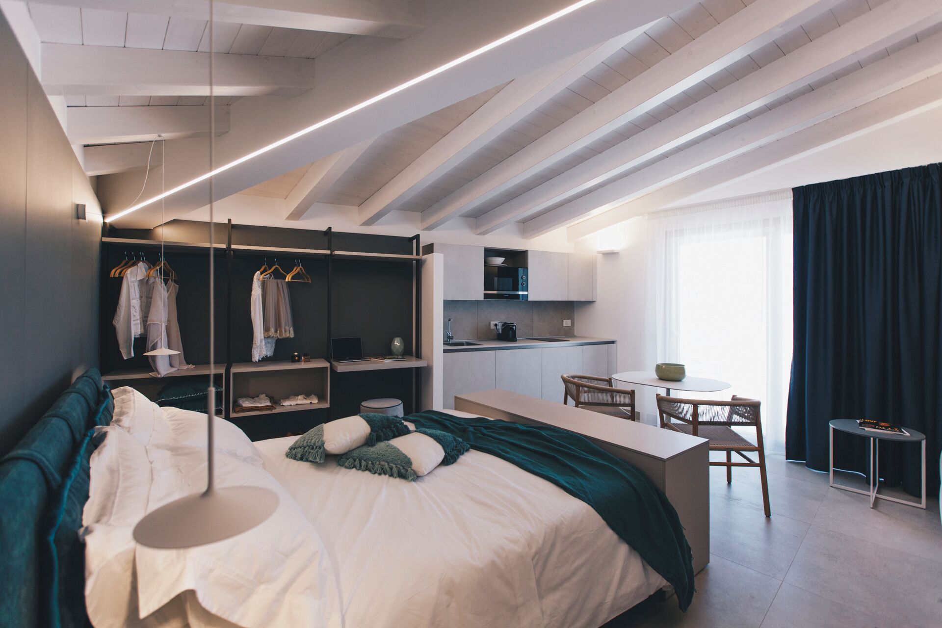 Een moderne slaapkamer met een groot bed, een inbouw-kast en een kitchenette.