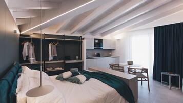 Een moderne slaapkamer met een groot bed, een inbouw-kast en een kitchenette.