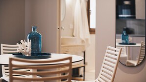 Ein Essbereich mit einem runden Tisch, weißen Stühlen, einer blauen Vase und einem dekorativen Korallenstück.
