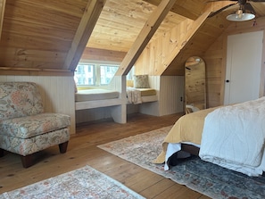 Un dormitorio acogedor en el ático, con techo de madera, cama, sofá y ventana.