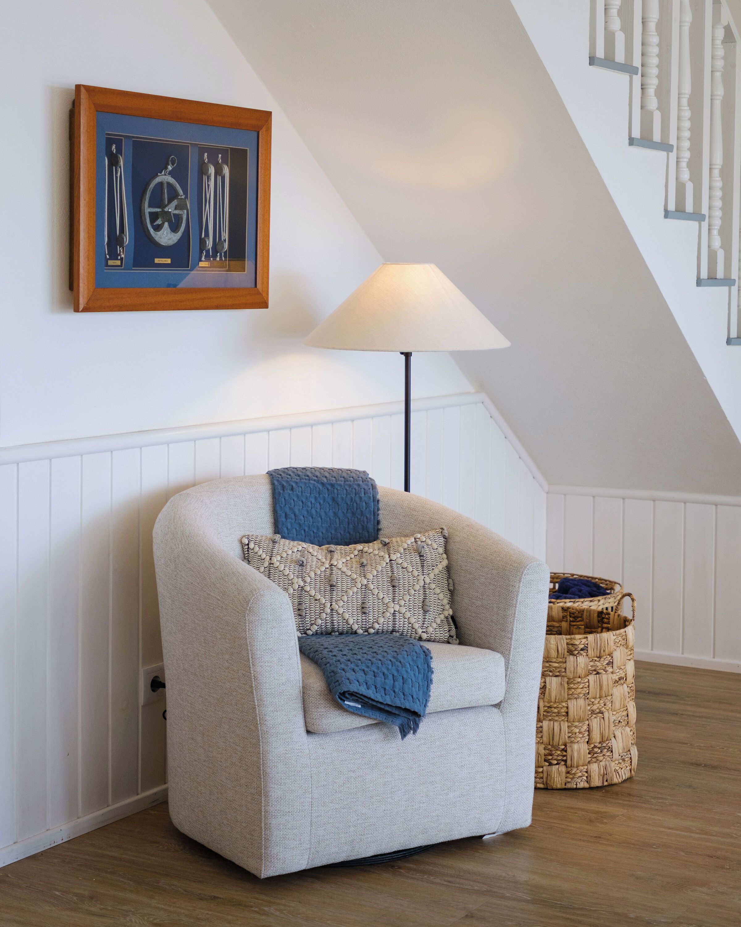 A cozy living room with a beige armchair, a blue throw blanket, and a woven basket on the floor.
