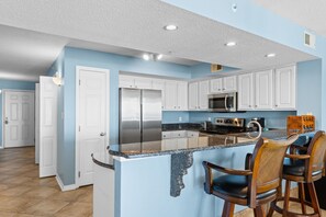 Una cocina moderna con armarios blancos, electrodomésticos de acero inoxidable y encimera de granito.