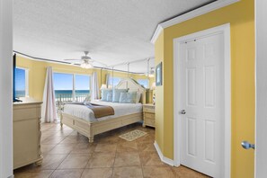 Un dormitorio con cama, mesitas de noche, cómoda y vistas a la playa.