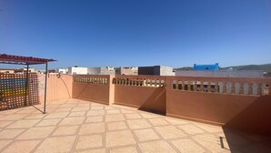 Une terrasse sur le toit, dotée d’un sol carrelé, d’une pergola et d’une clôture décorative.