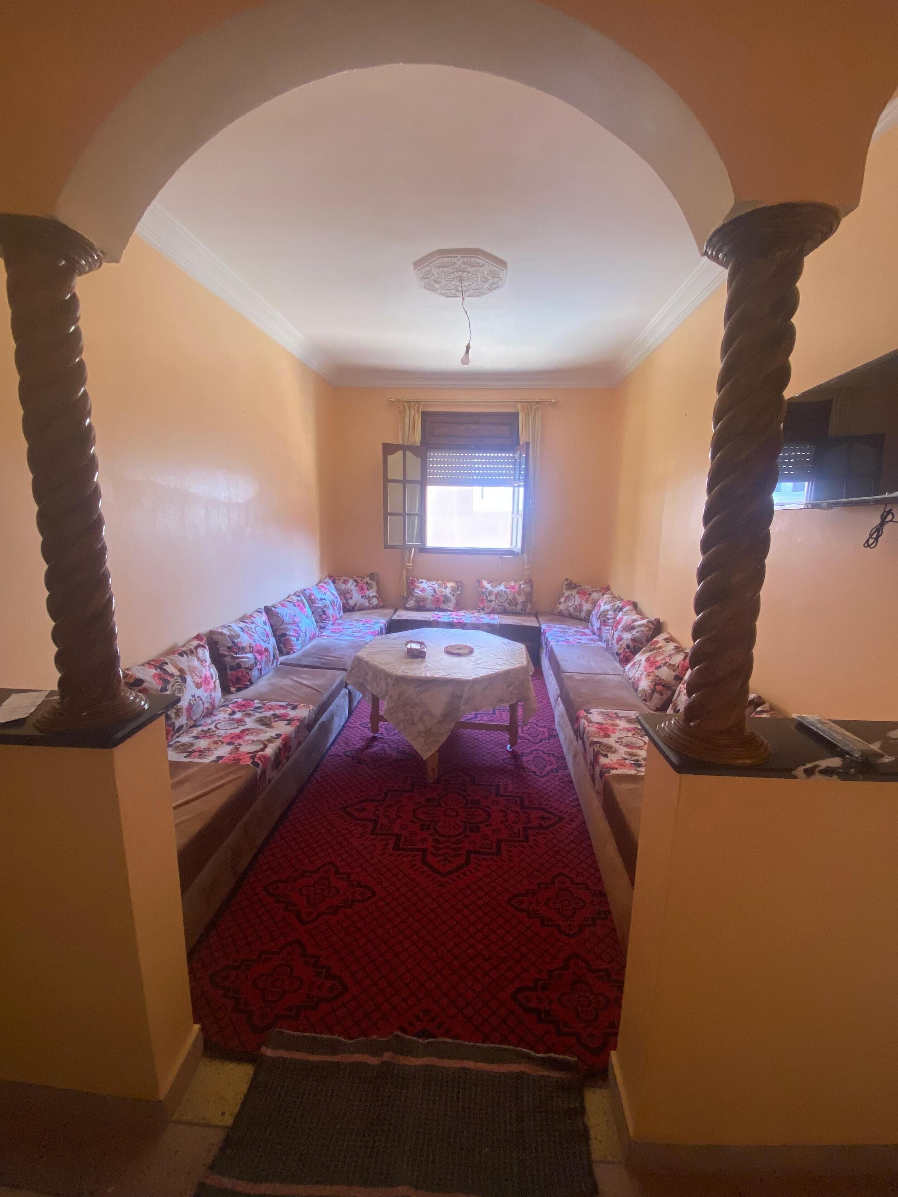 A room with a round table, sofas, and a patterned carpet.