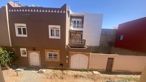 Un immeuble résidentiel à plusieurs étages, doté d’un balcon, d’une allée et d’une voiture garée.