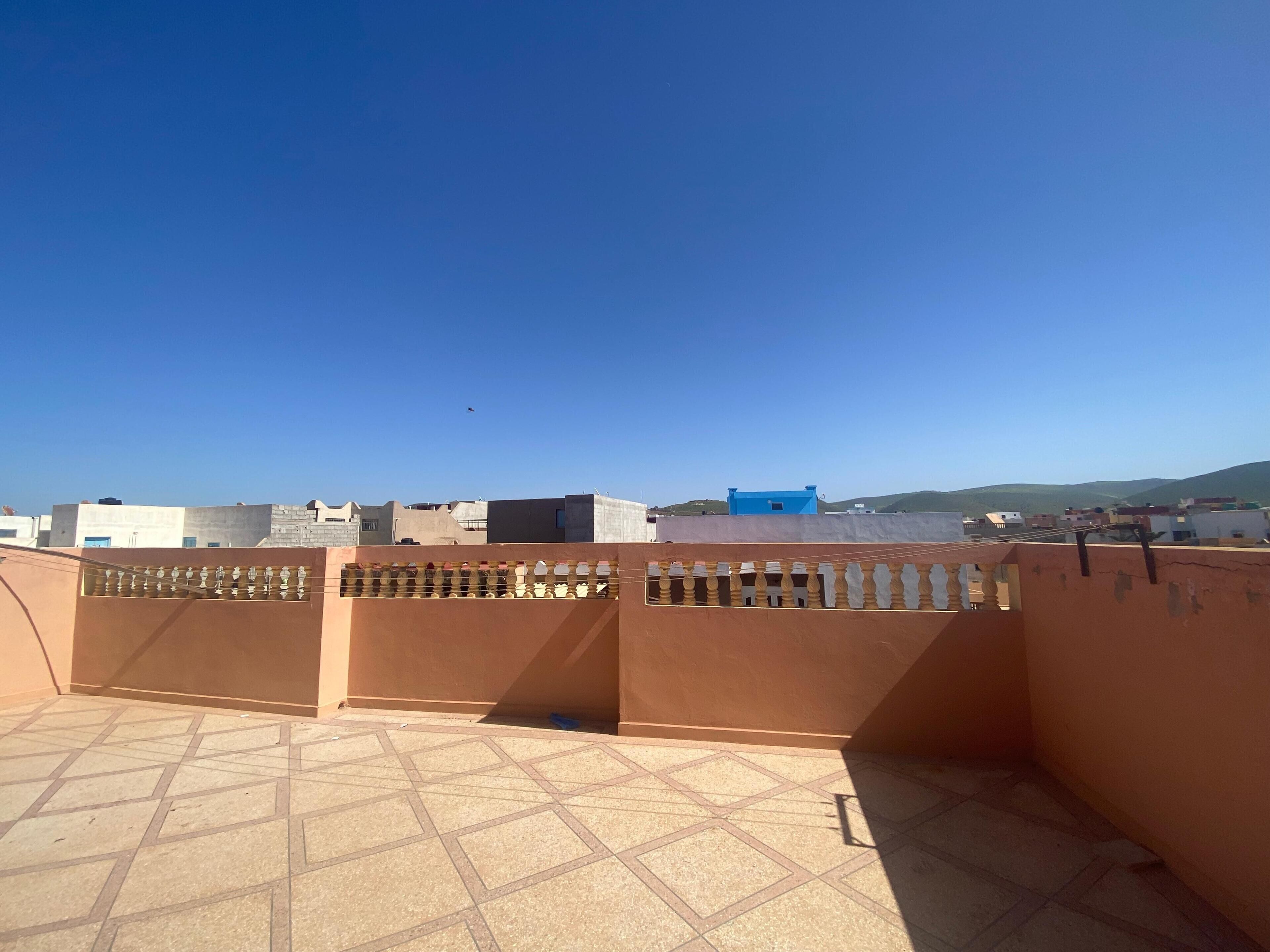 Una terrazza sul tetto con vista chiara sugli edifici circostanti e una collina in lontananza.