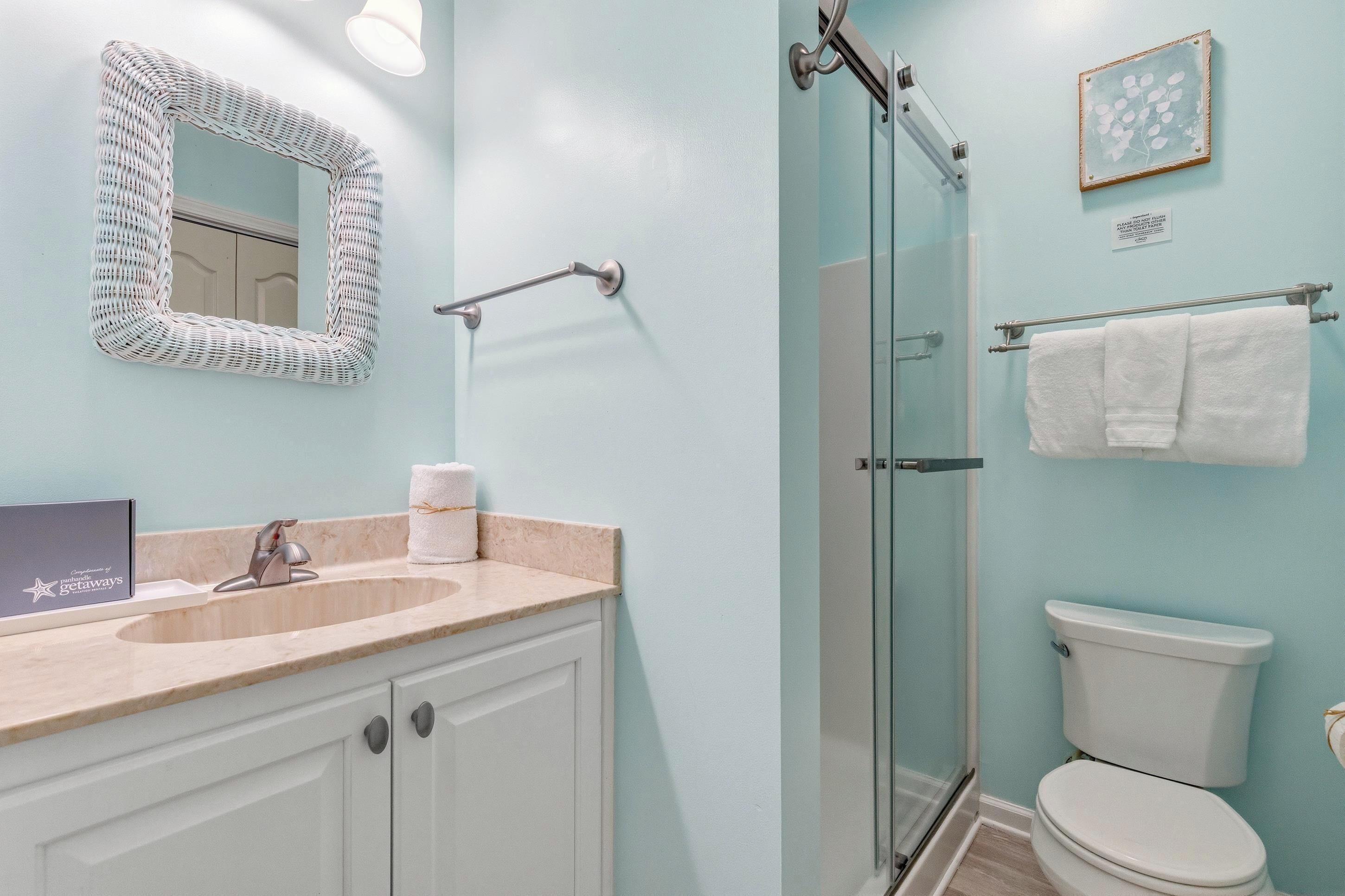 A bathroom with a sink, mirror, shower, and toilet.