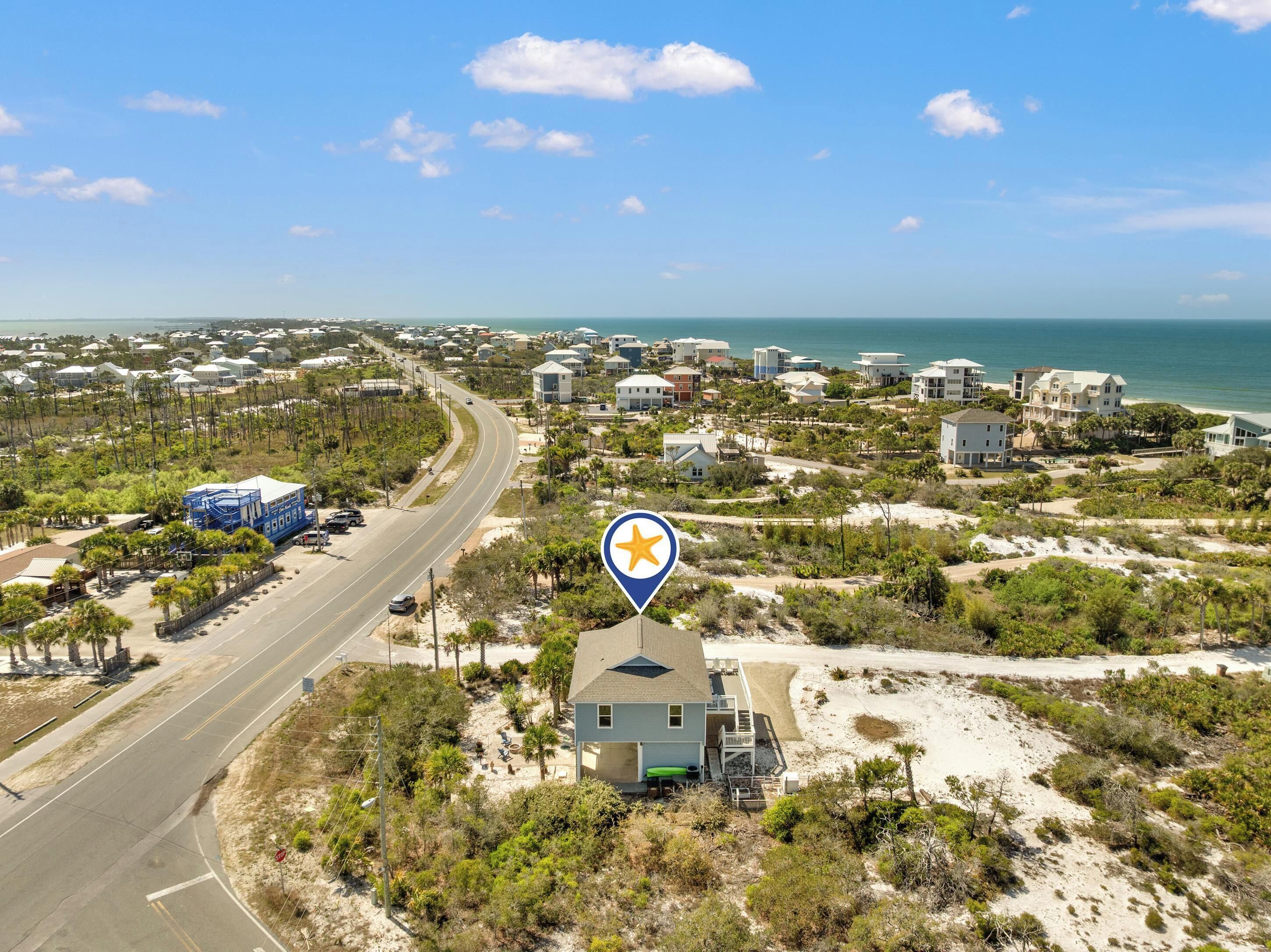 A coastal residential area with a road, houses, and a beach.