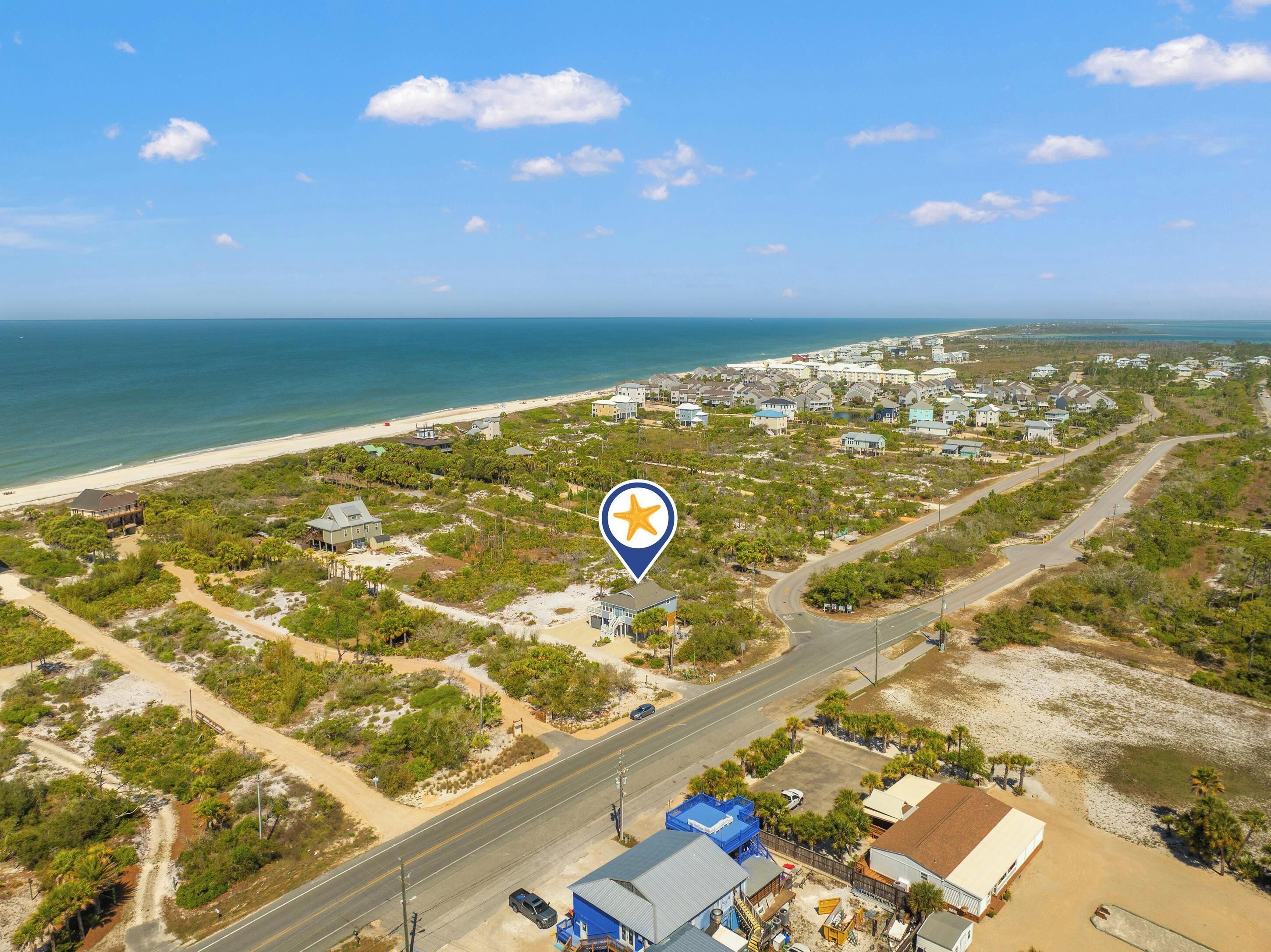 Vue aérienne d’une zone côtière comprenant une plage, des immeubles résidentiels et une route.