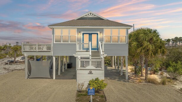 A two-story beachfront house with a balcony, a covered porch, and a small garden area. - Beach House - Salty Dolphin (Port St. Joe)