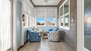 A sunroom with large windows, a ceiling fan, and a fire extinguisher. - Beach House - Salty Dolphin (Port St. Joe)