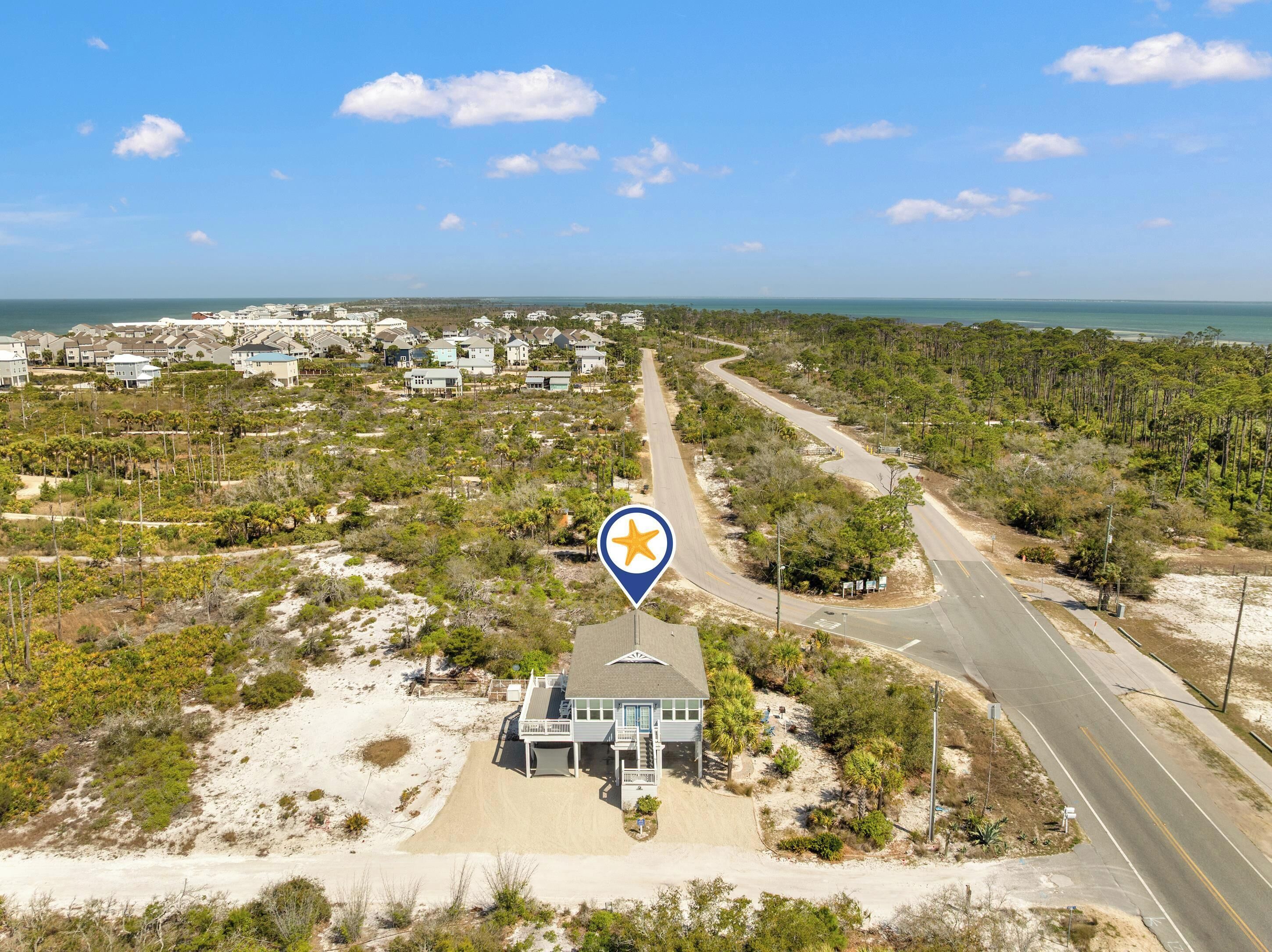 Una zona costera con una carretera, una casa de playa y un área residencial con viviendas.