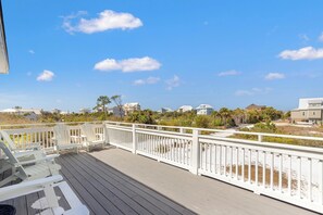 A wooden deck with white railings, beach houses in the background, and a clear blue sky. - Beach House - Salty Dolphin (Port St. Joe)
