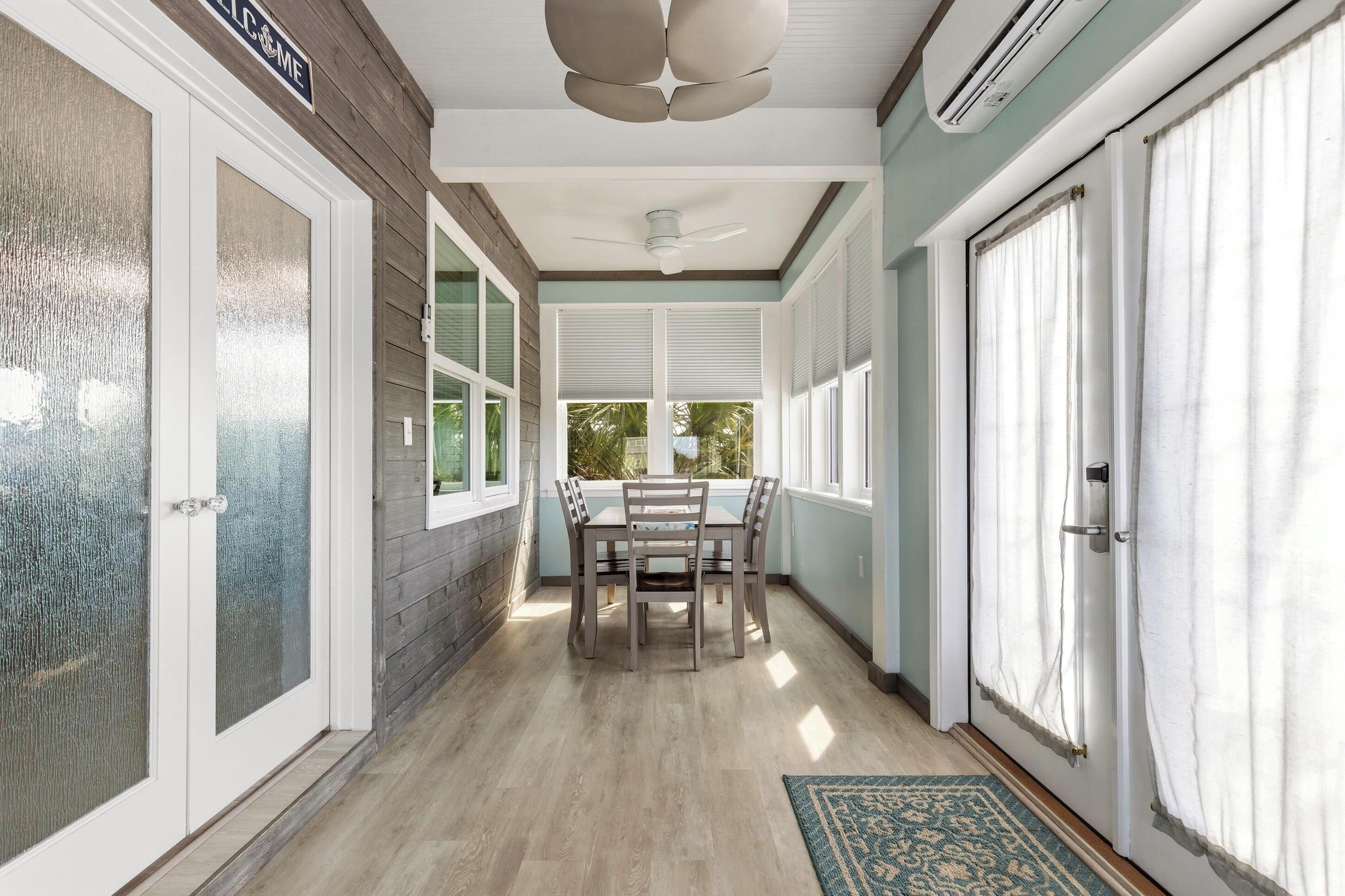A covered porch with a table and chairs, a ceiling fan, and a view of the outdoors.