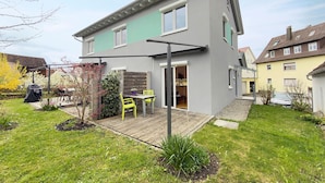 A modern two-story house with a patio, a sliding door, and a small garden area. - Rieke's Apartment with Private Terrace and Wi-Fi (Friedrichshafen)