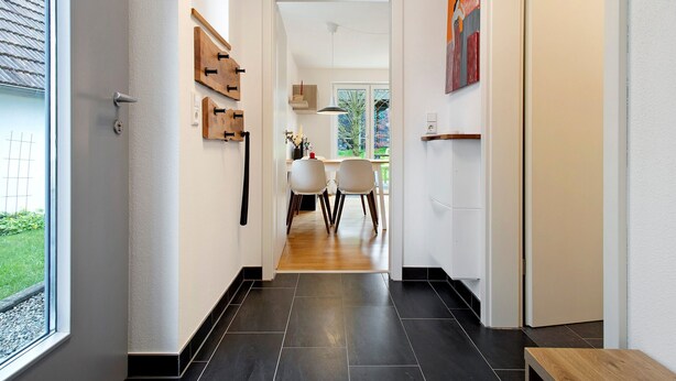 A hallway with a wooden bench, a dining area with chairs, and a door leading to another room. - Rieke's Apartment with Private Terrace and Wi-Fi (Friedrichshafen)
