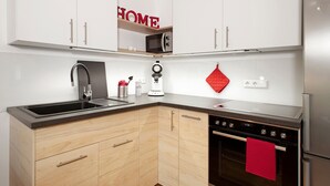 A modern kitchen with white cabinets, a stainless steel refrigerator, a microwave, and a coffee machine. - Rieke's Apartment with Private Terrace and Wi-Fi (Friedrichshafen)