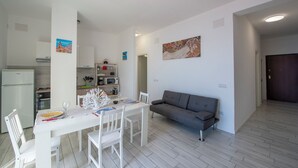 Una cocina moderna con comedor, un sofá gris y un cuadro en la pared.
