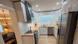 Eine moderne Küche mit weißen Schränken, einem eingebauten Ofen und einem Edelstahl-Kühlschrank.