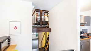 Una cocina moderna con horno integrado, encimera de madera y una escalera que sube a un nivel superior.