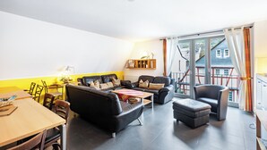 Una sala de estar moderna con sofá, sillones, una mesa de centro y un comedor con sillas y una mesa.