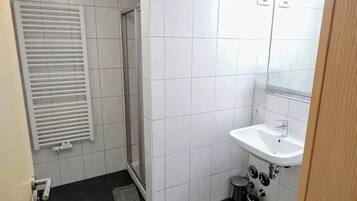 Une petite salle de bain avec une douche, un lavabo et des toilettes.