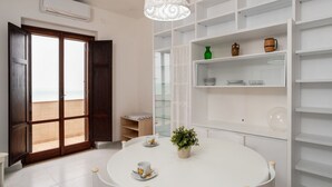 A modern room with a round table, a potted plant, and a glass cabinet. - San Menaio Apartment by Rentbeat (Vico del Gargano)