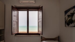 A room with a bed, a window with open shutters, and a wall-mounted artwork. - San Menaio Apartment by Rentbeat (Vico del Gargano)