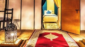 A tent-like room with a bed, a red carpet, and a lantern. - Merzouga Luxury Tented (Merzouga)