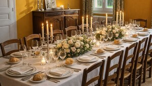 A dining room with a long table set for a meal, flanked by wooden chairs, a wooden cabinet, and a window with curtains. - Le Château de Chambois ✦ Confidential ✦ Families ✦ Seminars (Gouffern en Auge)