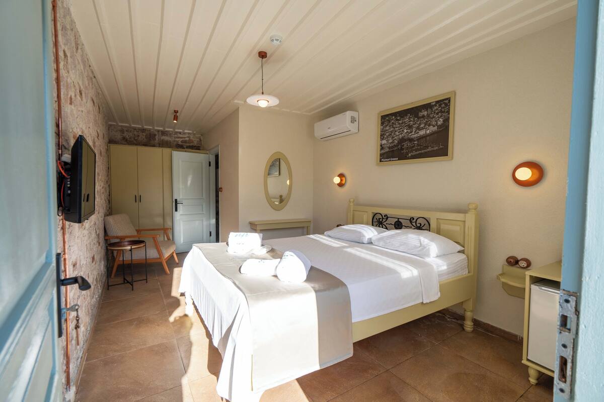 Un dormitorio con cama, mesitas de noche, un espejo y un aire acondicionado instalado en la pared.