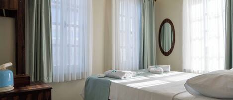 A bedroom with a wooden bed, a bedside table, a hanging light fixture, and a window with curtains.