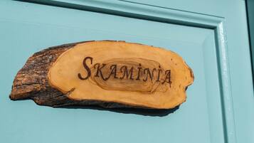 Un letrero de madera con el nombre 'Skamintia' en una puerta color turquesa.