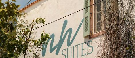 A building with a sign reading 'SUITES' and a window with green shutters.