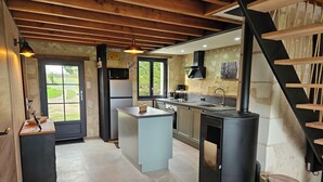 Een moderne keuken met een centraal eiland, een ingebouwde kookplaat en een groot raam.