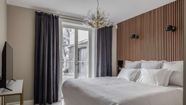 A bedroom with a bed, curtains, a television, and a view of the outside. - Villa Strandliv invites you to experience an extraordinary stay in a one-of-a-kind residence. (Gustavsberg)