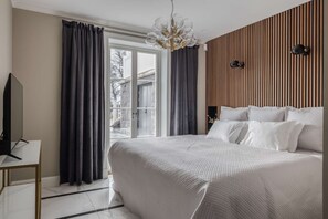 Une chambre à coucher avec un lit, des rideaux, une télévision et une vue sur l’extérieur.