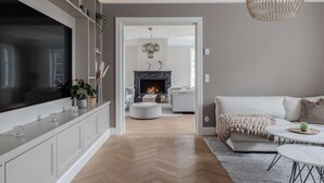 A modern living room with a fireplace, a sofa, a coffee table, and a TV on a cabinet. - Villa Strandliv invites you to experience an extraordinary stay in a one-of-a-kind residence. (Gustavsberg)