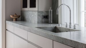 A modern kitchen with a marble countertop, stainless steel sink, and a large window providing natural light. - Villa Strandliv invites you to experience an extraordinary stay in a one-of-a-kind residence. (Gustavsberg)