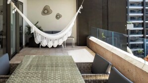 Ein Balkon mit Hängematte, Sitzgelegenheit und Blick auf ein Gebäude.