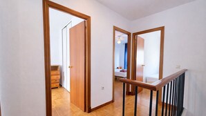 Um corredor com portas de madeira e escada com corrimão preto.