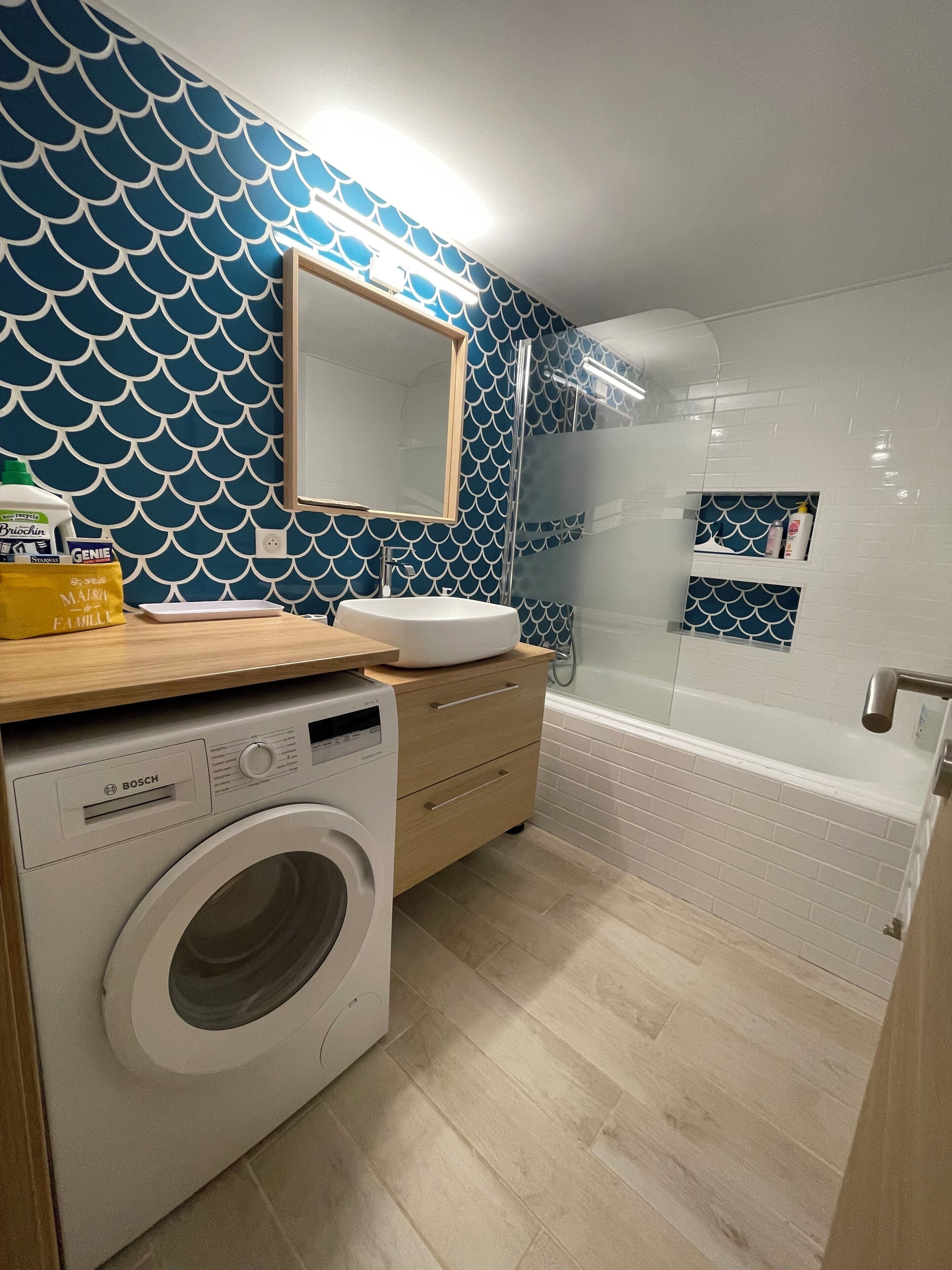 A modern bathroom with a washing machine, a sink, and a shower.