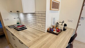 Een moderne keuken met een houten aanrecht, witte kastjes, een betegelde achterwand en een ingebouwd spoelbak.