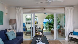 A living room with a sofa, coffee table, and a view of the outdoor patio area. - Sapphire Beach 104 2 Bedroom Apts (St. Lawrence Gap)