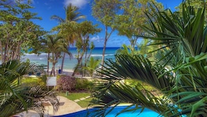 A tropical resort with a pool, palm trees, and a view of the ocean. - Sapphire Beach 104 2 Bedroom Apts (St. Lawrence Gap)