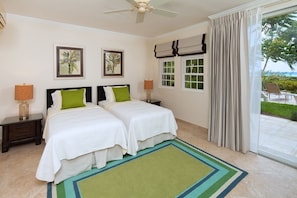 A hotel room with two beds, a ceiling fan, a window with curtains, and artwork on the wall. - Sapphire Beach 116 2 Bedroom Apts (St. Lawrence Gap)