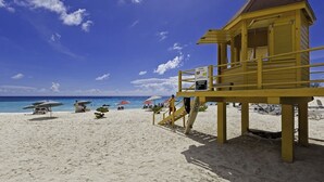 Ein Rettungsturm am Strand mit Sonnenschirmen und Liegestühlen.