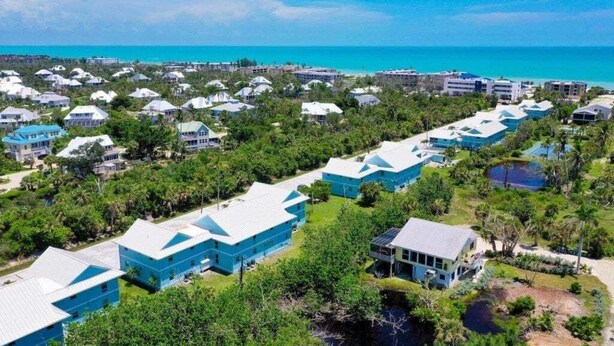 Ein Resort mit mehreren blauen Gebäuden, einem Strand und freiem Blick auf den Ozean.