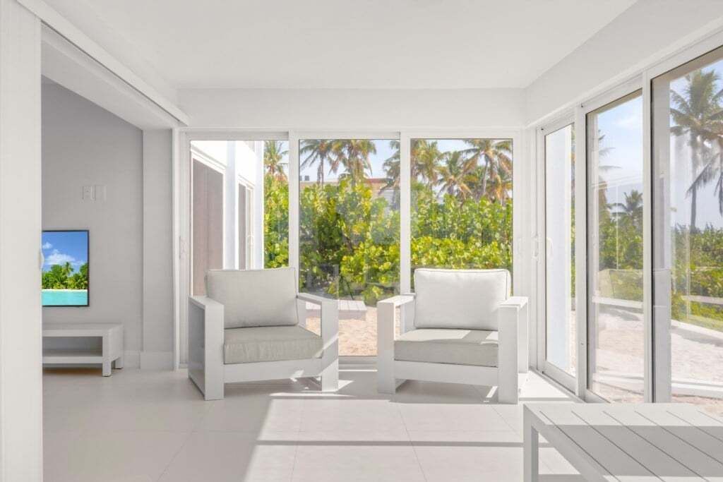 A bright room with white walls and a large window overlooking palm trees.